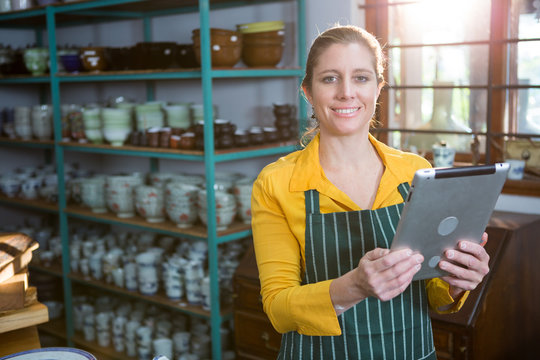 Portrait of female potter using digital tablet