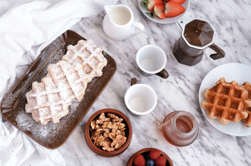 Belgian waffles with different topping , raspberry ,strawberry, blueberry,honey,    icing sugar and walnuts for perfect  breakfast. Delicious homemade dessert background.Top view.