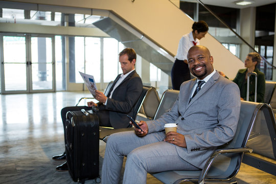 Businessman using mobile phone in waiting area at airport terminal