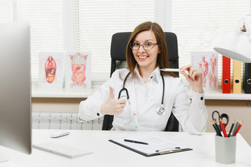 Female doctor sitting at desk with medical documents, clinical thermometer with normal temperature...