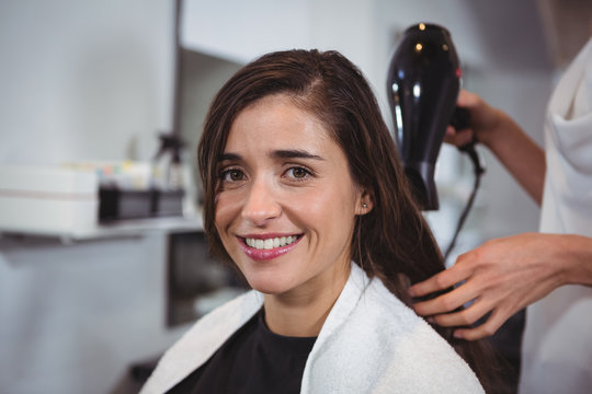 Pretty woman getting her hair dried with hair dryer