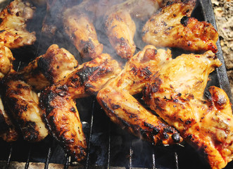 Grilled chicken on the grill. Close up shot of red meat and chicken legs grilled during picnic