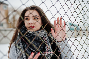 Close up portrait of brunette girl in scarf against cage.