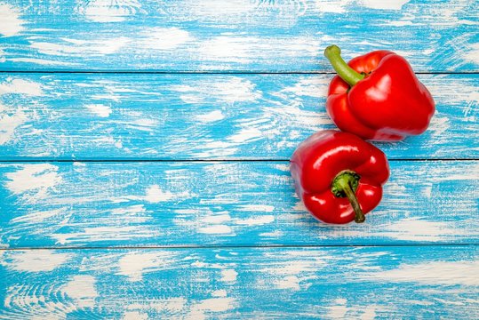 Two red peppers lying on a blue background