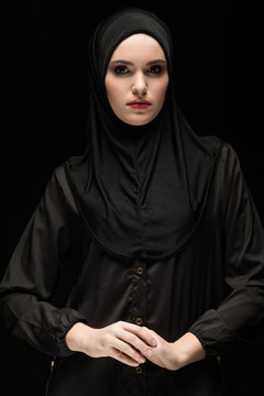 Beautiful young woman wearing black hijab as conservative fashion concept on black background holding hand on hand