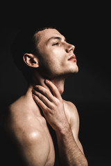 Fototapeta premium Side view thoughtful male stripped to waist while holding neck by arm. Muse concept
