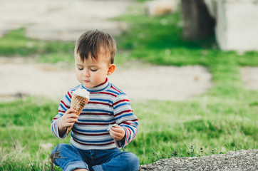 little cute boy eating ice cream three years very appetizing, amid nature, green grass