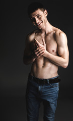 Fototapeta na wymiar Portrait of cheerful man with brilliant smile and attractive body crossing hands. Happy bare-chested guy concept. He isolated on black background