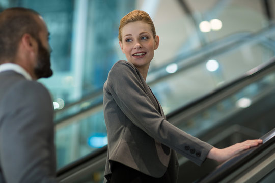 Businesspeople interacting with each other while going up on escalator