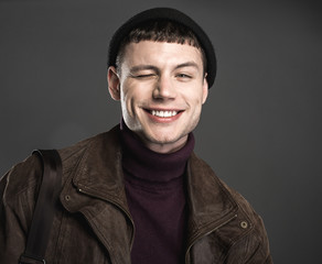 Portrait of beaming man with nice smile blinking. He isolated on black background. Cheerfulness concept