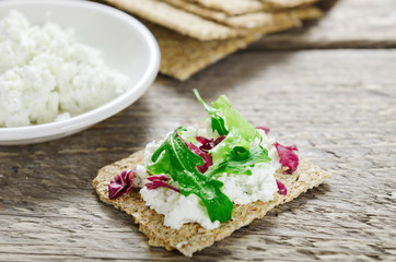 Crisp bread with cheese and greens on a wooden table. Dietary dish