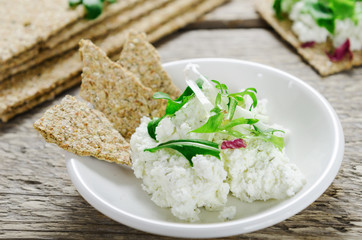 Cream cheese with greens and crisp bread on a white plate. Healthy food.