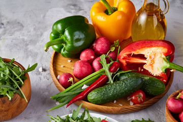 Still life of wooden plate with vegetables on white textured background, close-up, selective focus