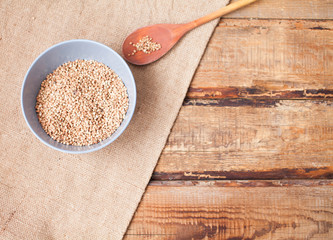 Buckwheat groats in a bowl and wooden scoop with buckwheat on gr