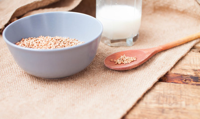 Buckwheat groats in a bowl and wooden scoop with buckwheat