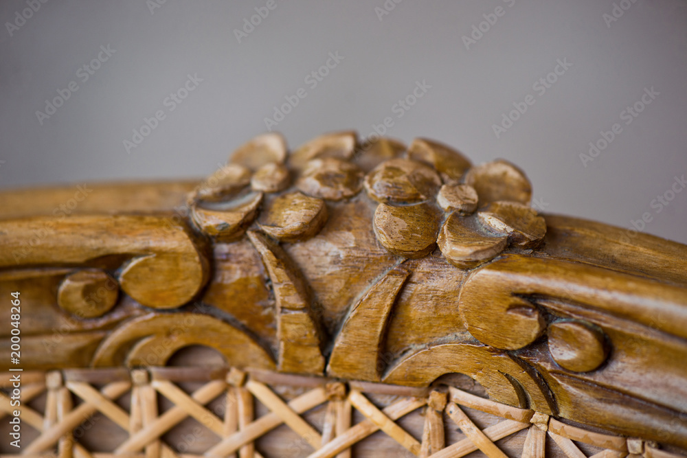 Wall mural detail of furniture, carving in the form of flowers on an old rattan chair.