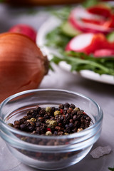 Glass bowl with dried allspice seeds with salad plate on textured background, selective focus, vertical