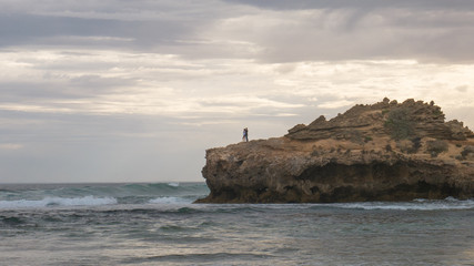 Young lovers watching the surf from a rocky outcrop at Portsea in Victoria, Australia
