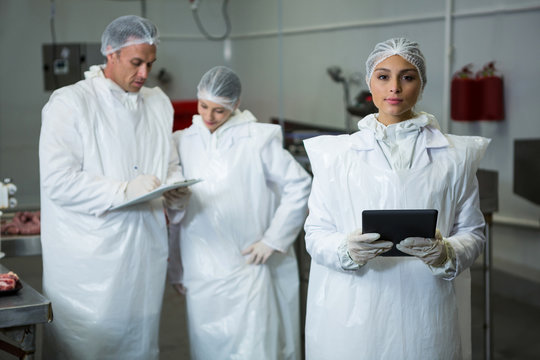 Technician holding digital tablet at meat factory
