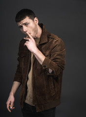 Portrait of assertive young man smoking cigar. He isolated on black background. Steepness concept