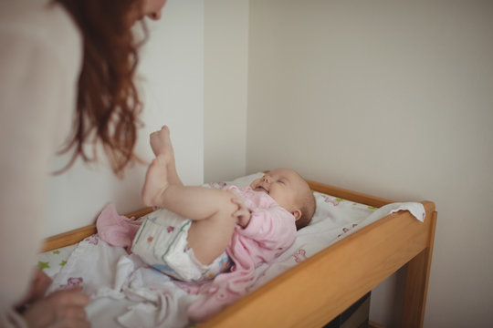Cropped image of mother playing with baby in crib