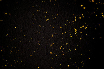 Gold glitter texture on a black background. Holiday background. Golden explosion of confetti....