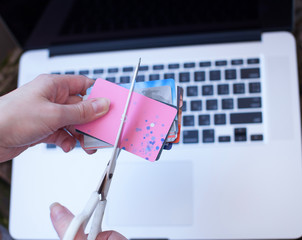 Female hands cutting credit card with scissors