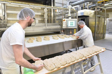 Lebensmittelindustrie: Großbäckerei - Arbeiter backen Brot // Food industry: Bakery - workers...