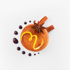 Cookie decorated with lemon zest, chocolate drops, cinnamon and anise star on a white background. Pastry styling tips concept.
