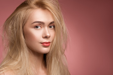 Fototapeta premium Portrait of sad lady with disheveled hair looking at camera. Copy space in right side. Isolated on rose background