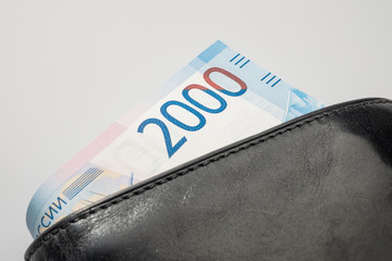 Black natural leather wallet isolated on white background. Expensive man's purse closeup. New russian ruble banknote, Two thousand rubles.