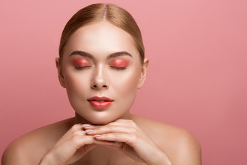 Portrait of well cared girl demonstrating makeup with closed eyes. Copy space in right side. Isolated on rose background