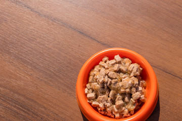 Canned food for cats or dogs in a orange plastic bowl