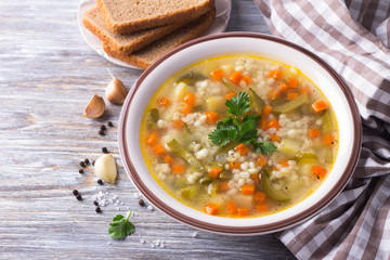 Vegan soup with pickled cucumbers and pearl barley, rassolnik. traditional homemade Russian cuisine. on a wooden table. free space