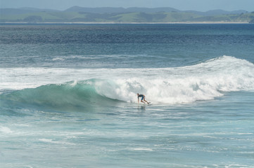 young man surfing on ocean waves on cloudy day, Leigh beach, New Zealand