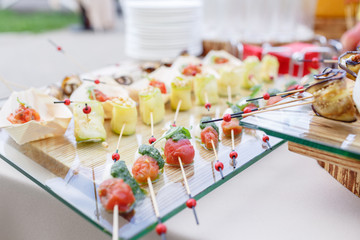Zucchini rolls with pine nuts. Cherry tomatoes,mozzarella and Basil on skewers. . Pesto sauce. Tasty buffet table. Summer party outdoor.
