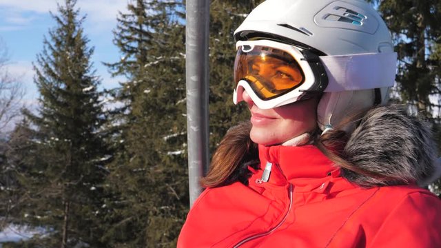 Adorable woman smiles sitting on the ski lifter in the mountains