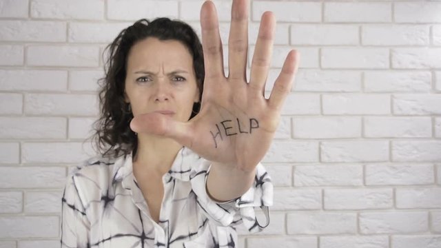 The hostage. Domestic violence. A woman shows an inscription on the palm of the HELP.