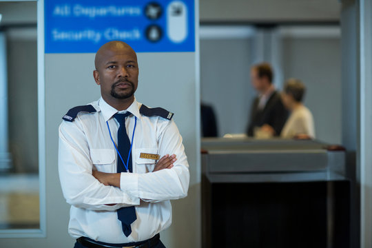 Airport security officer standing with arms crossed in airport terminal