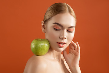 Youthfulness concept. Portrait of calm naked lady with smooth skin looking at apple on her shoulder. Isolated on background