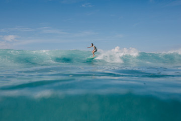 young man riding blue ocean waves on surfboard