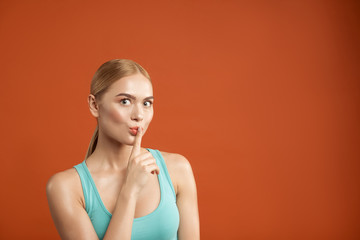 Silence concept. Portrait of well groomed woman looking at camera and holding her index finger on...