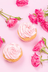 Cupcake with pink cream decoration and roses on pink pastel background.