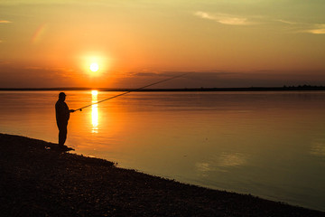  Silhouettes of fishermen against the background of a colorful sunset.
