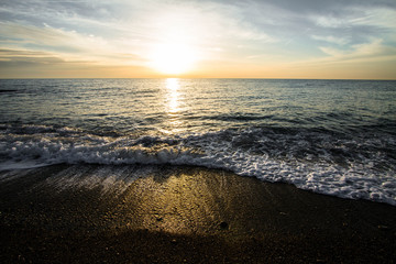 Coastal waves at sunset. Colorful sunset on a sea beach.