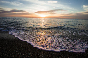Coastal waves at sunset. Colorful sunset on a sea beach.