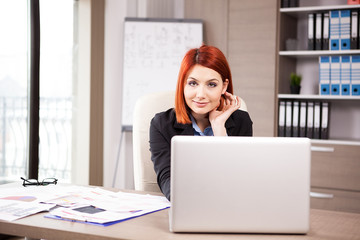 Smiling businesswoman at the desk working on the computer