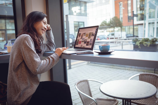 Beautiful woman using laptop while having coffee