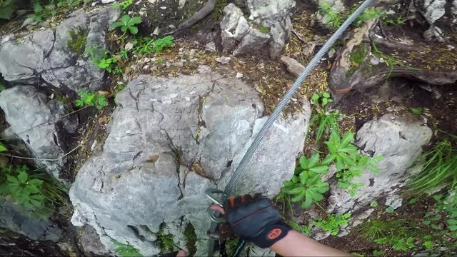 POV - a man climbs up a cliff in a forest