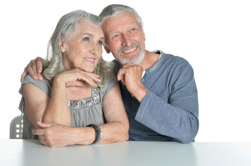 Portrait of hugging senior couple sitting at table